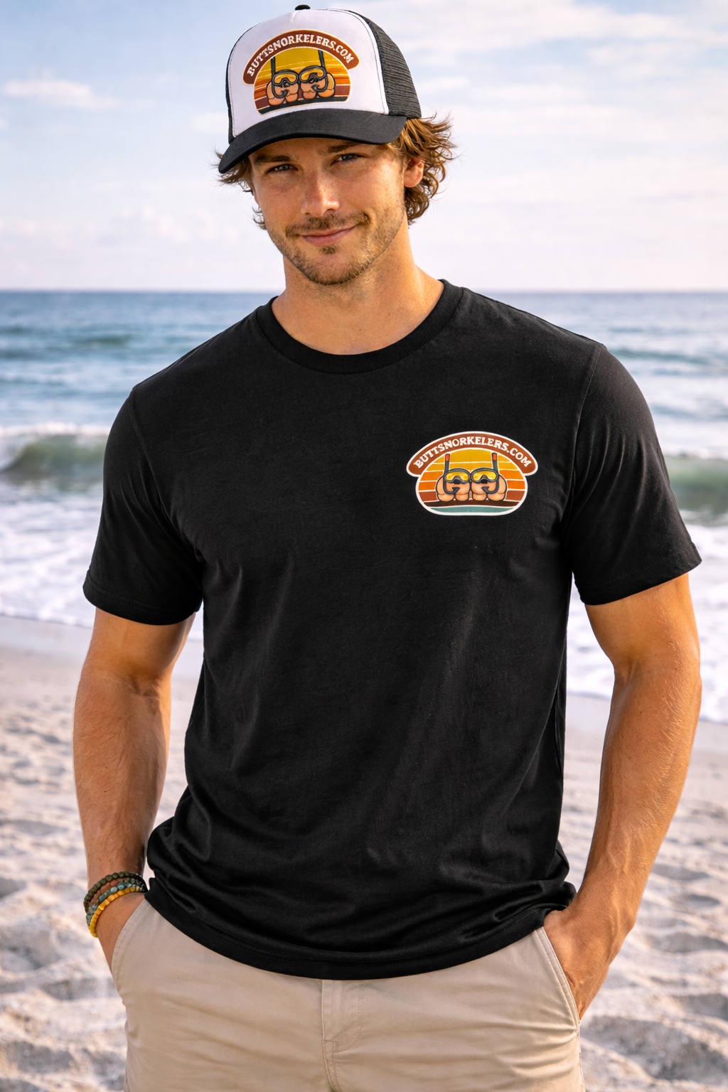 ButtSnorkelers classic tee — man on beach wearing black shirt with logo on chest and hat